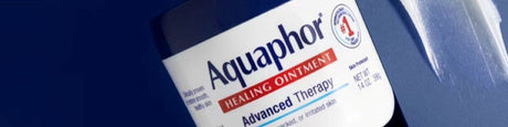 Aquaphor collection: Woman applying moisturizer, hand squeezing lotion from a white and blue tube.