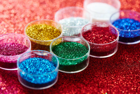 Vibrant Art Glitter collection: pots of red, gold, silver, green, blue, and pink glitter for wholesale.
