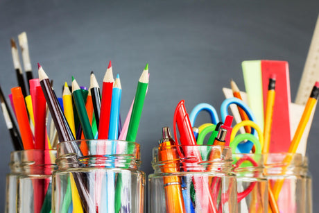 Vibrant art pens, pencils, and markers in glass jars, ideal for creative professionals.