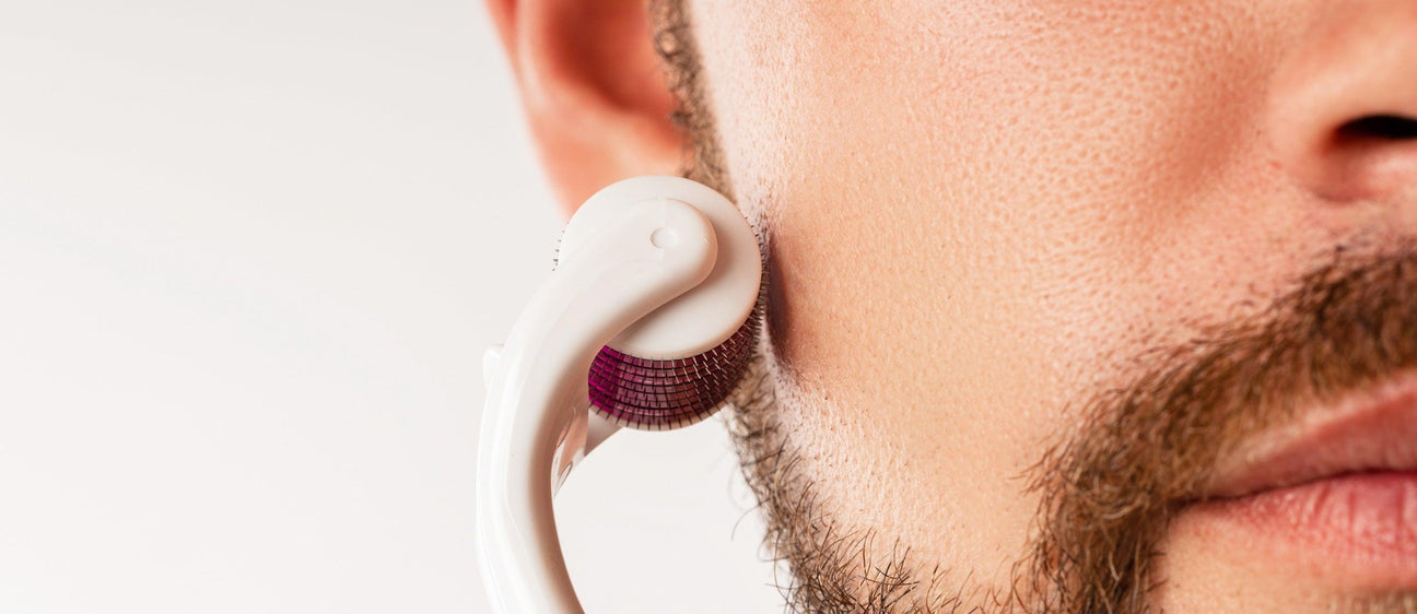 Close-up of a man using a white and purple derma roller on his cheek, highlighting professional face care tools.