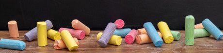 Assorted colorful chalk sticks on a wooden surface, evoking a creative, educational theme for business applications.