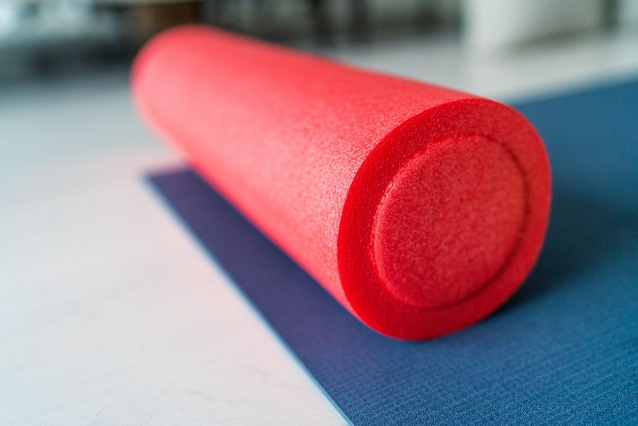 Vibrant red foam roller on a blue mat, showcasing durable texture for professional use.