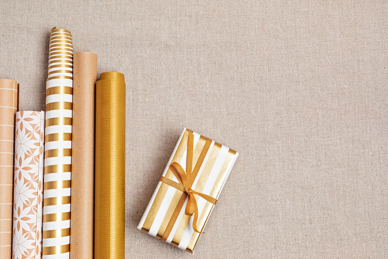 Premium gold and kraft gift wrap rolls with a matching wrapped present, ideal for bulk B2B orders.