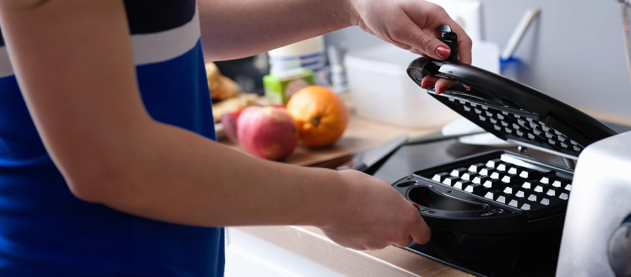 Modern black waffle maker in use, ideal for commercial kitchens.