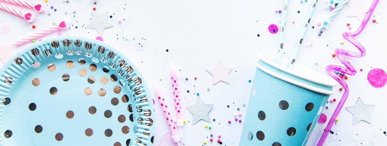 Wholesale party tableware: blue polka dot plates, cups, straws, and pink birthday candles for festive events.