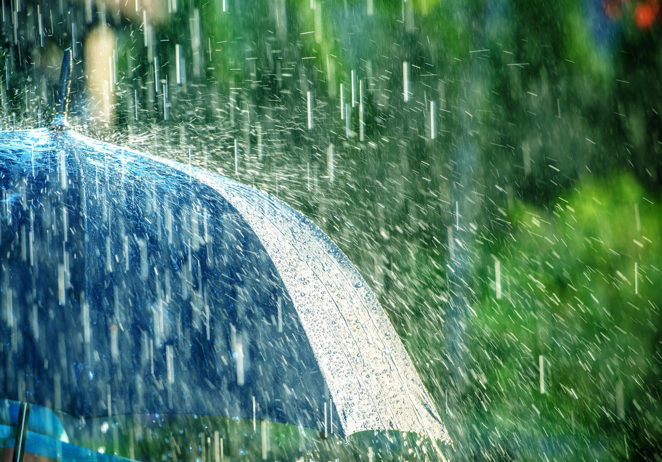 Blue umbrella in heavy rain, showcasing durable weather protection for winter collections.