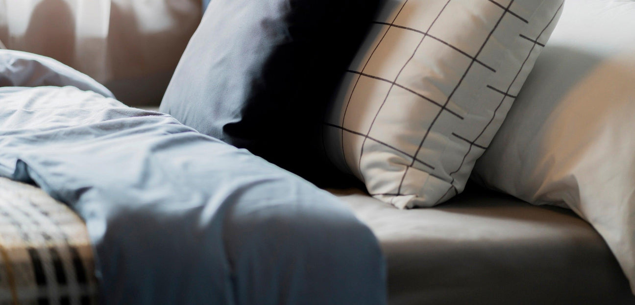 Modern bedding collection featuring grey, black, and white pillows with a grid pattern, ideal for hospitality.